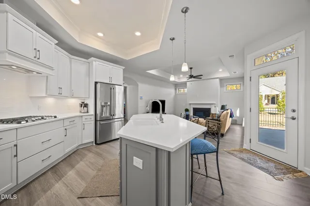 a kitchen with stainless steel appliances kitchen island granite countertop a dining table chairs refrigerator and microwave