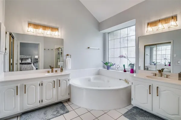 a bathroom with a bathtub a sink a mirror a vanity and windows