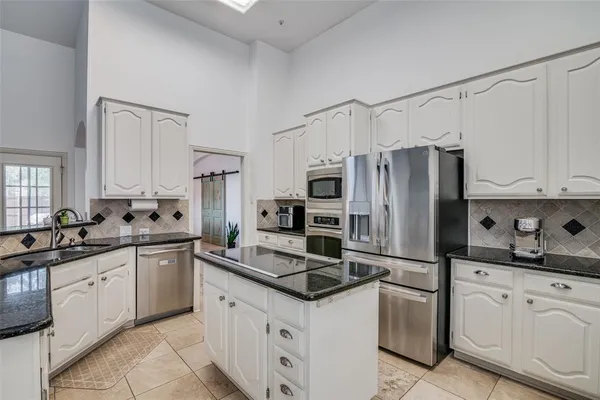 a kitchen with granite countertop a refrigerator sink and cabinets