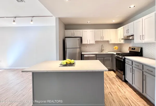 a kitchen with kitchen island sink refrigerator and white cabinets