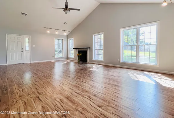 an empty room with wooden floor fireplace and windows