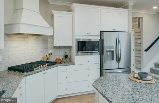 a kitchen with granite countertop white cabinets and stainless steel appliances