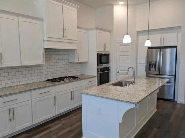 a kitchen with stainless steel appliances granite countertop a sink a stove and a refrigerator