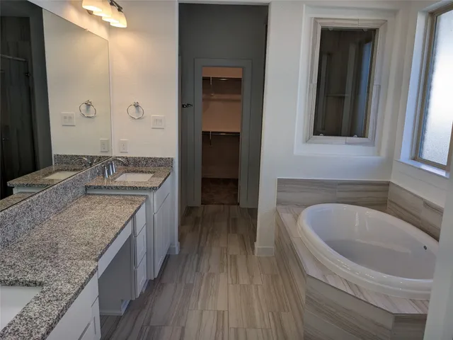 a bathroom with a granite countertop tub sink and mirror