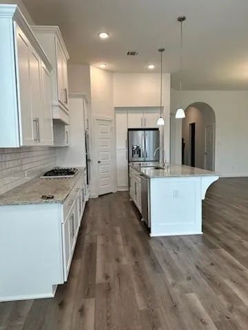a view of kitchen with stainless steel appliances granite countertop a stove a refrigerator a sink and a oven