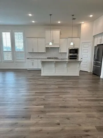 a large kitchen with stainless steel appliances granite countertop a lot of counter space and wooden floors