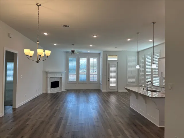 a view of an empty room with wooden floor and a kitchen