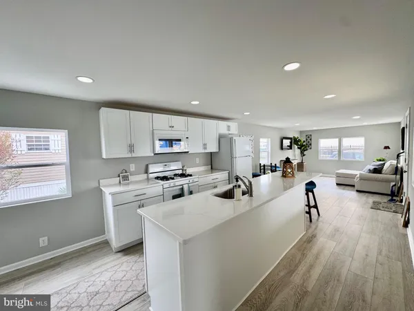 a living room with stainless steel appliances furniture a kitchen view and a livingroom