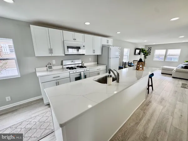 a large white kitchen with cabinets a sink a window and stainless steel appliances