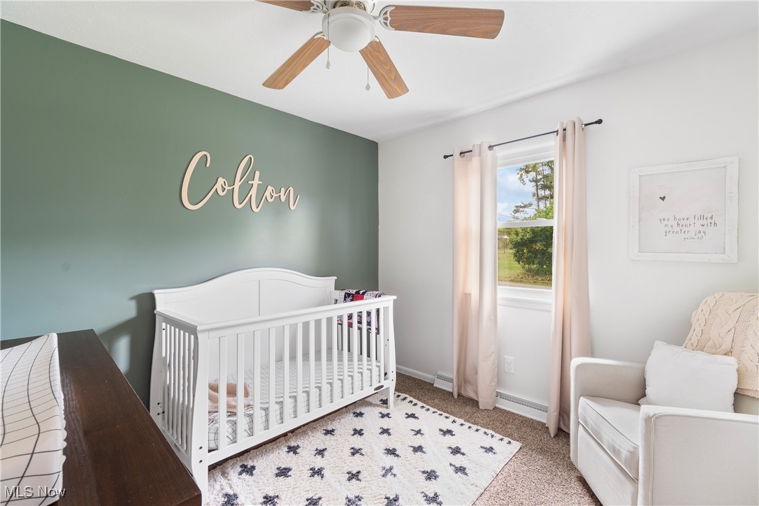 1701 Rheam Road Clinton, OH 44216 - Photo 21 of 31 Bedroom with a baseboard radiator, carpet, ceiling fan, and a nursery area