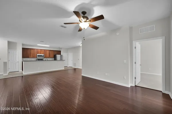 a view of empty room with wooden floor and fan