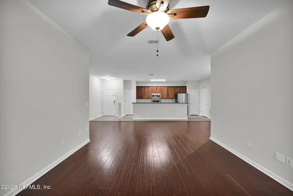 an empty room with wooden floor chandelier fan and windows
