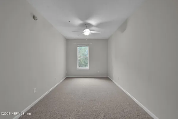 an empty room with a window and a ceiling fan