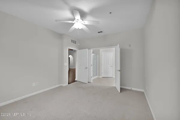 a view of an empty room with a chandelier fan