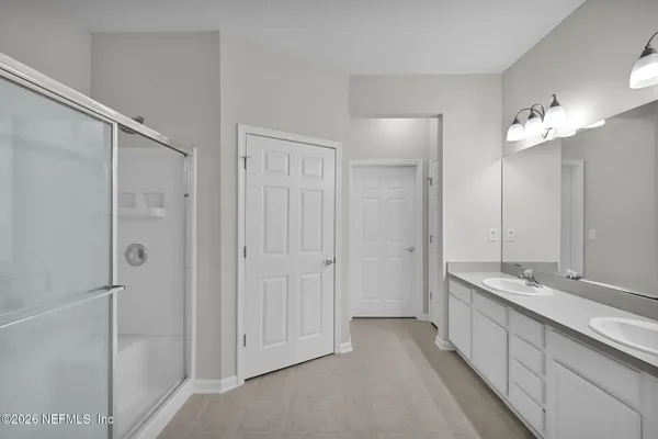 a bathroom with a double vanity sink a mirror and a shower