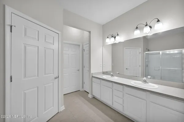 a spacious bathroom with a double vanity sink a mirror and a shower
