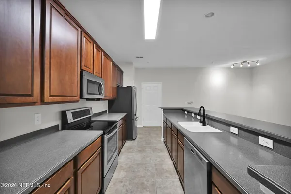 a kitchen with stainless steel appliances granite countertop a sink a stove and a refrigerator