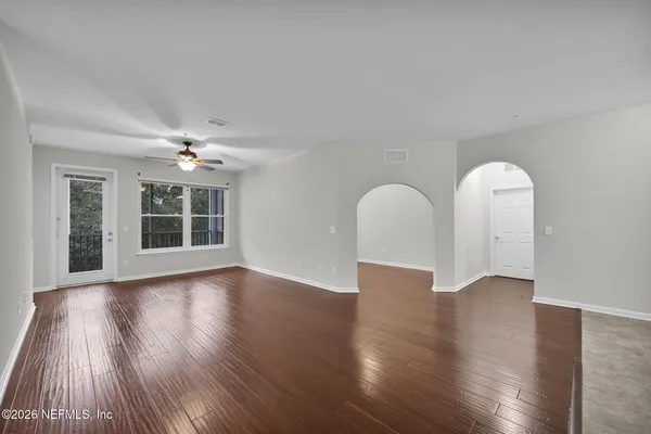 a view of an empty room with wooden floor and a window