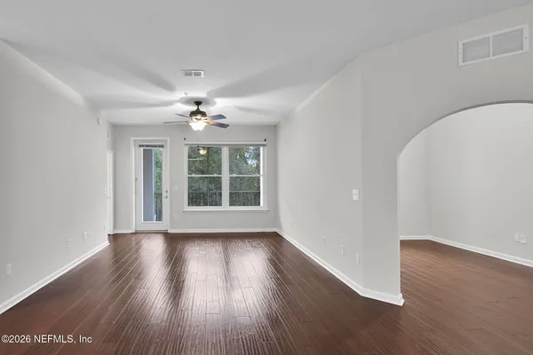 a view of an empty room with wooden floor and a window