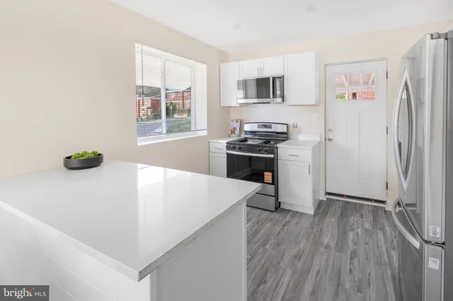 a kitchen with stainless steel appliances a white refrigerator a stove a sink and a microwave