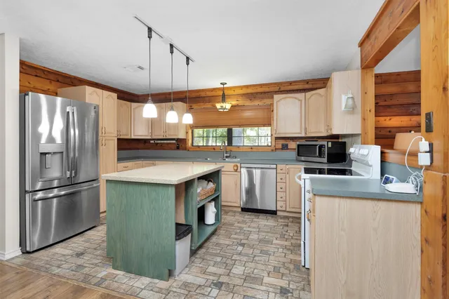 a kitchen with stainless steel appliances granite countertop a refrigerator a sink a stove and a refrigerator
