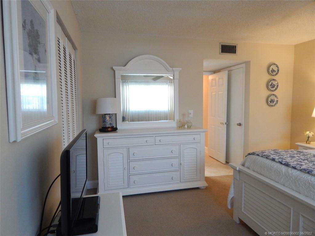 2950 Southeast Ocean Boulevard, Unit 74 Stuart, FL 34996 - Photo 17 of 39 a bedroom with a bed and a mirror on dresser