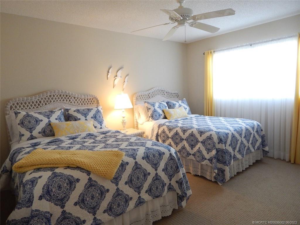 2950 Southeast Ocean Boulevard, Unit 74 Stuart, FL 34996 - Photo 22 of 39 a bedroom with two beds and a chandelier