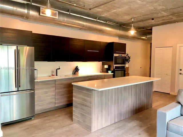 a kitchen with stainless steel appliances kitchen island a sink refrigerator and microwave