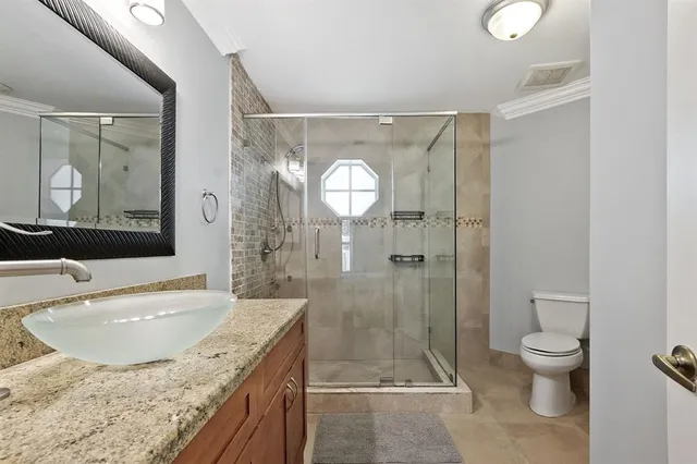 a bathroom with a granite countertop sink a toilet and shower