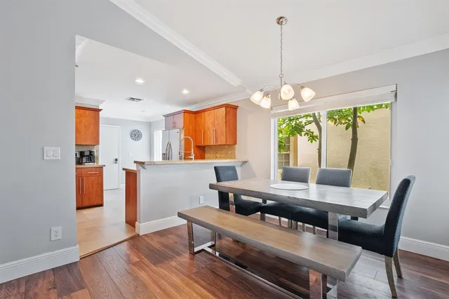 a dining room with wooden floor a chandelier a wooden table and chairs