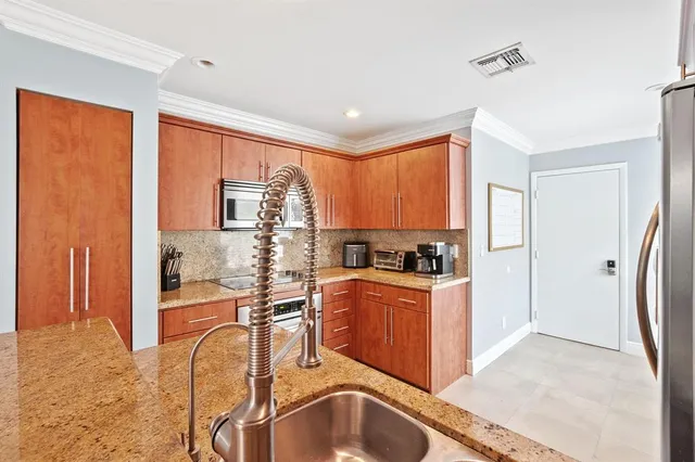 a kitchen with stainless steel appliances granite countertop a refrigerator a stove top oven a sink with island and windows