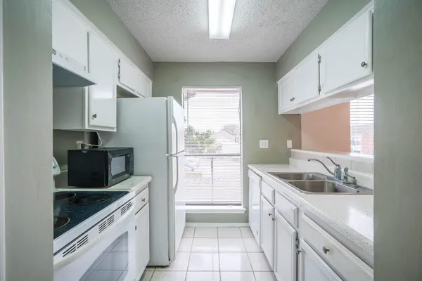 a kitchen with granite countertop a sink stove and refrigerator