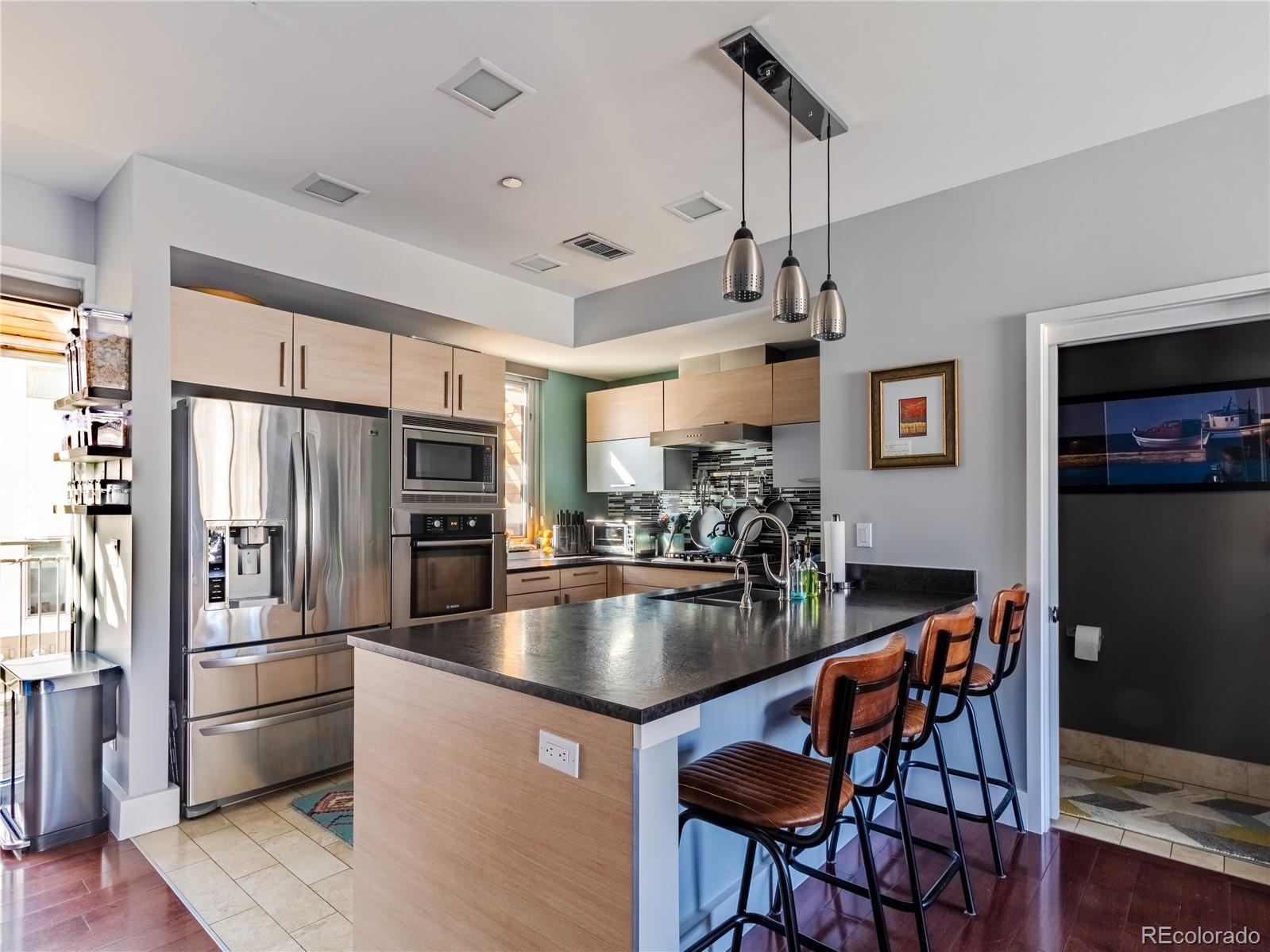 a kitchen with stainless steel appliances granite countertop a refrigerator a stove a sink dishwasher a dining table and chairs with wooden floor