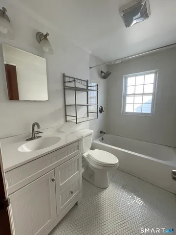 a bathroom with a toilet a sink a tub and mirror