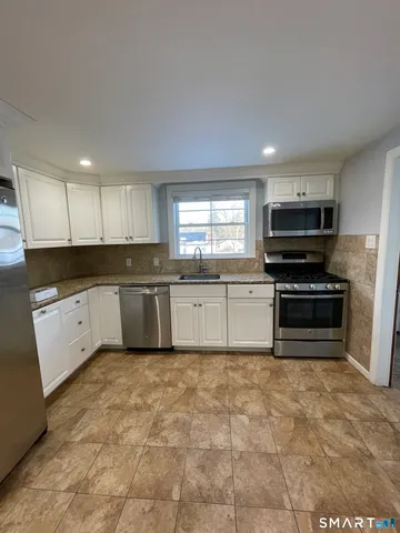 a kitchen with granite countertop a stove a sink and a microwave