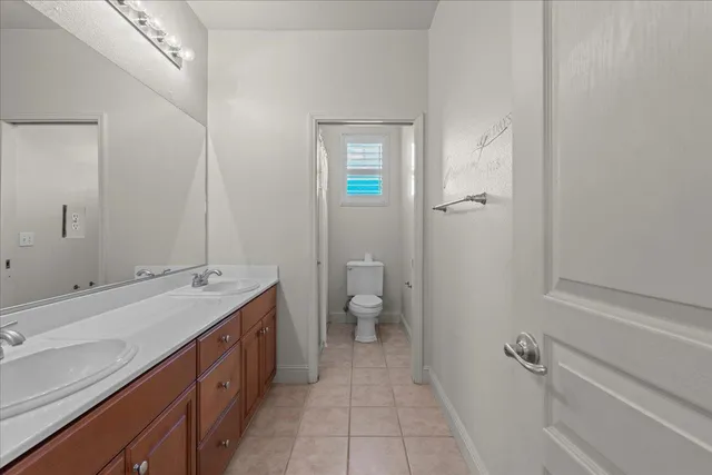 a spacious bathroom with a double vanity sink a toilet and a mirror