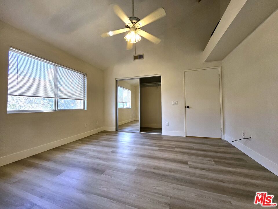 7254 Brienza Place Rancho Cucamonga, CA 91701 - Photo 15 of 17 an empty room with wooden floor chandelier fan and windows