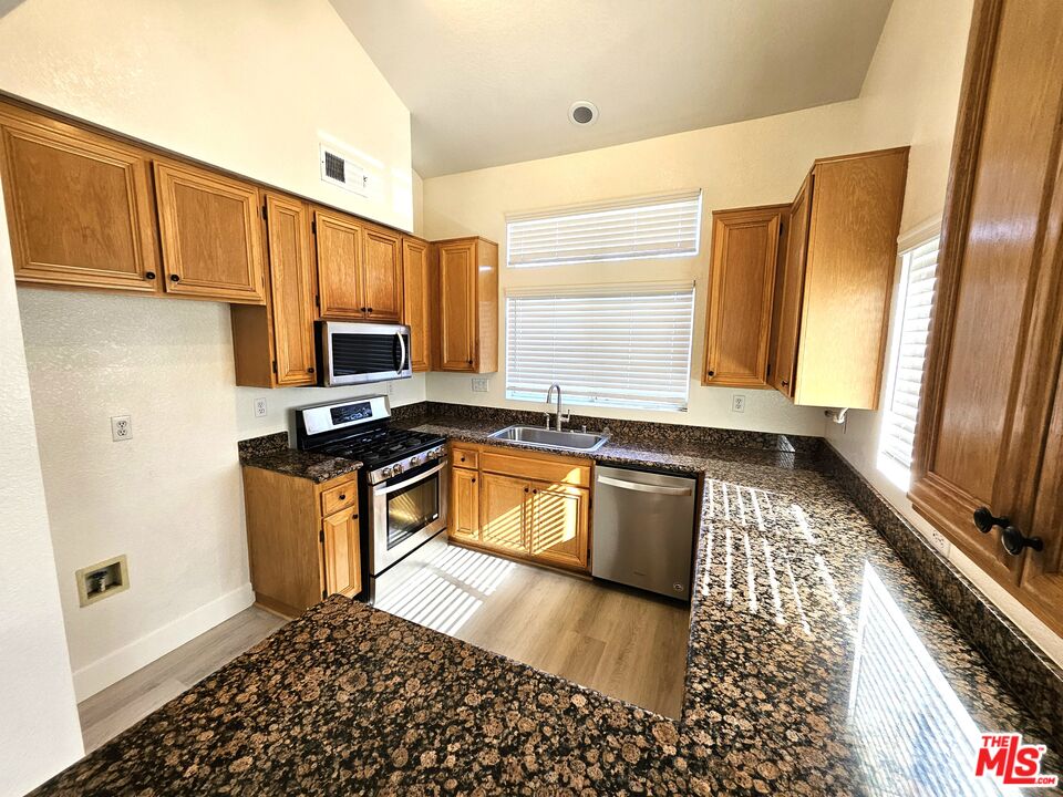 7254 Brienza Place Rancho Cucamonga, CA 91701 - Photo 2 of 17 a kitchen with granite countertop a stove a sink and a microwave