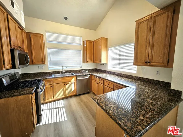 a kitchen with stainless steel appliances granite countertop a sink a stove a counter space and cabinets