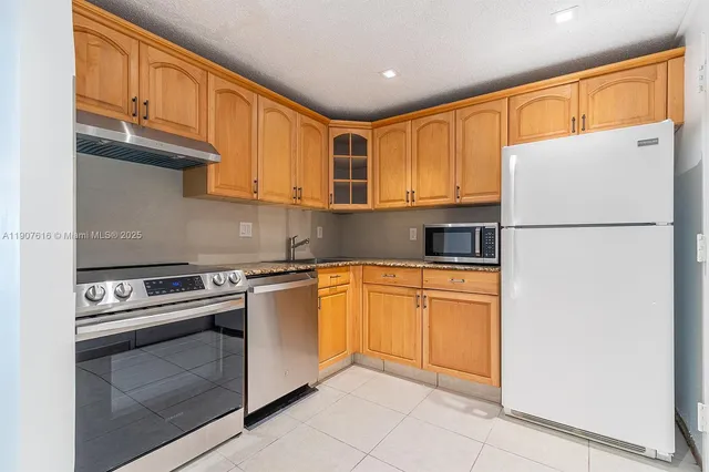 a kitchen with stainless steel appliances granite countertop a refrigerator sink stove and cabinets