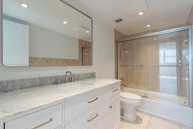 a bathroom with a shower sink vanity mirror and toilet