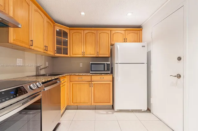 a kitchen with a refrigerator a stove top oven and cabinets