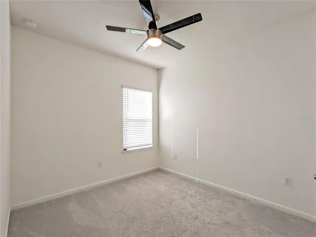 an empty room with a window and a fan
