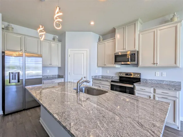 a kitchen with stainless steel appliances granite countertop a sink a stove counter space and cabinets