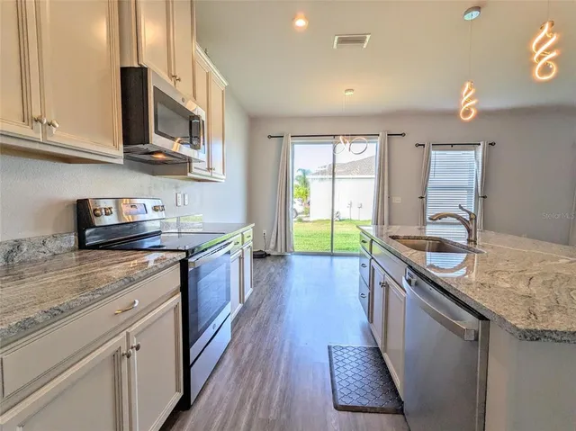 a kitchen with stainless steel appliances granite countertop a sink stove and cabinets