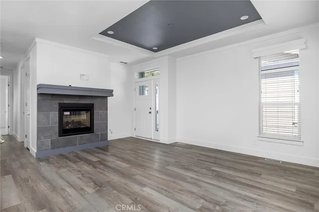 a view of an empty room with wooden floor fireplace and a window