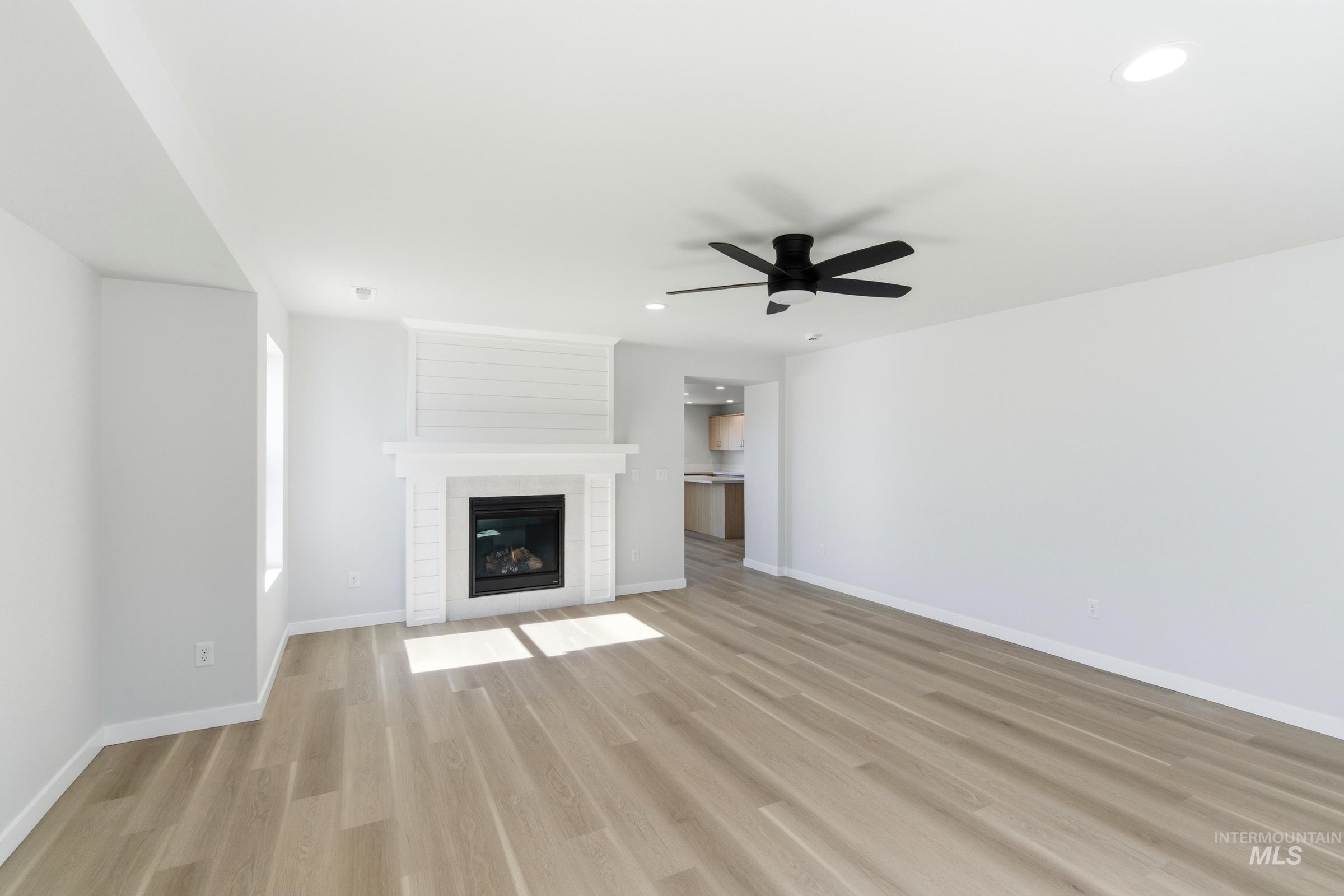 13677 Redway Court Caldwell, ID 83607 - Photo 13 of 35 Living area featuring wood-finish flooring, a contemporary fireplace with a shiplap accent wall, a matte black ceiling fan, recessed lighting, and white baseboards