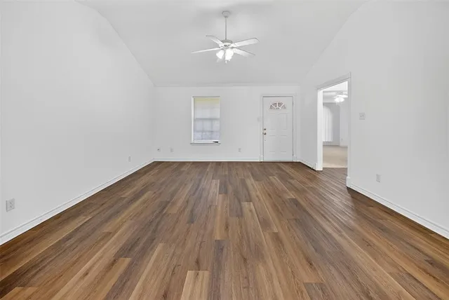 an empty room with wooden floor and a ceiling fan