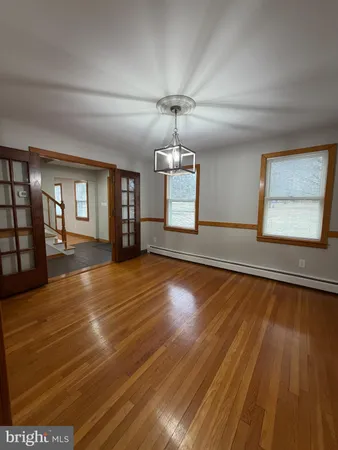 a view of an empty room with window and wooden floor
