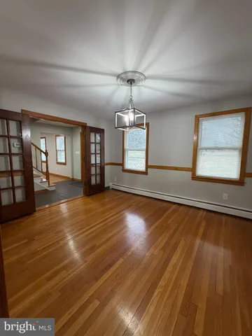 a view of an empty room with window and wooden floor